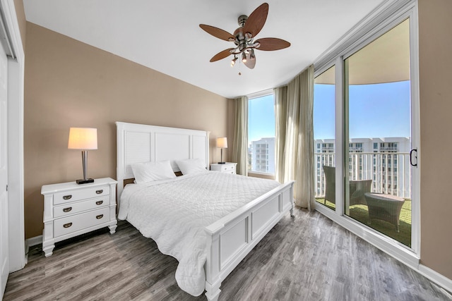 bedroom with wood-type flooring, a wall of windows, access to outside, and ceiling fan