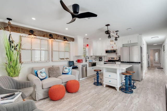 living room with light hardwood / wood-style flooring, ceiling fan, crown molding, and sink