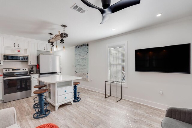 kitchen with stainless steel appliances, white cabinets, a center island, light hardwood / wood-style floors, and a breakfast bar area