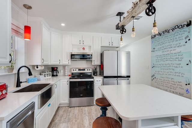 kitchen with stainless steel appliances, white cabinets, a center island, light hardwood / wood-style floors, and hanging light fixtures