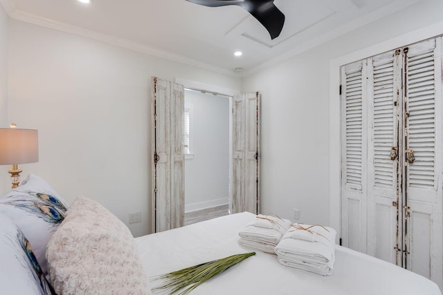 bedroom with ceiling fan, a closet, and ornamental molding