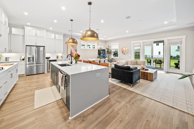 kitchen featuring stainless steel fridge with ice dispenser, pendant lighting, white cabinets, and a kitchen island with sink