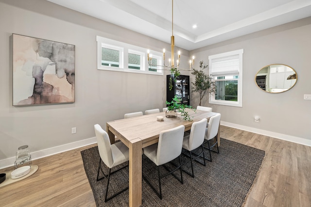 dining room with a chandelier, hardwood / wood-style floors, and a raised ceiling