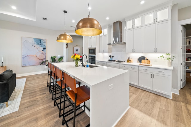 kitchen with white cabinets, wall chimney exhaust hood, and hanging light fixtures