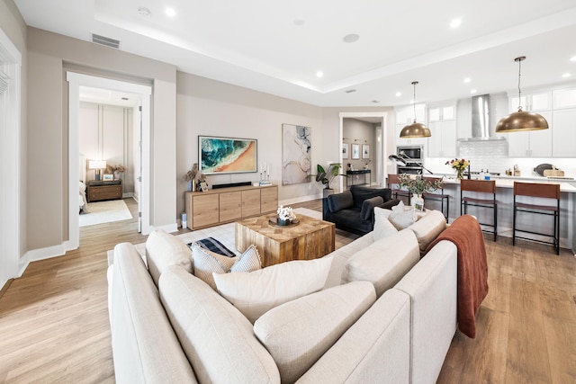 living room featuring light wood-type flooring and a tray ceiling