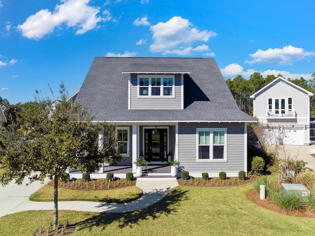 view of front facade with covered porch, a garage, and a front lawn