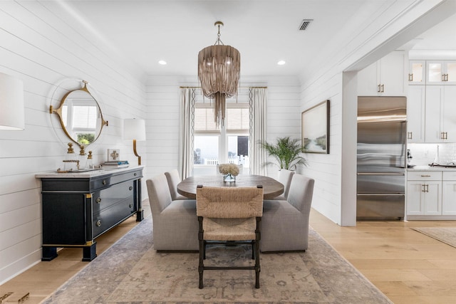 dining space with light hardwood / wood-style flooring and wood walls