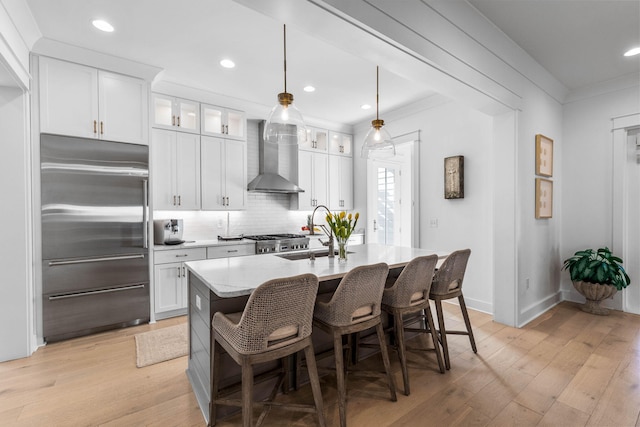 kitchen featuring wall chimney exhaust hood, sink, stainless steel built in fridge, light hardwood / wood-style floors, and white cabinetry