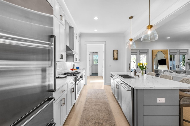 kitchen featuring a kitchen breakfast bar, high end appliances, sink, a center island with sink, and white cabinetry