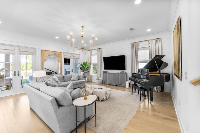 living room with a notable chandelier, french doors, crown molding, and light hardwood / wood-style flooring