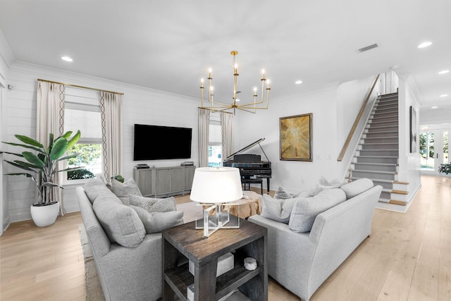 living room featuring light hardwood / wood-style flooring, ornamental molding, and an inviting chandelier