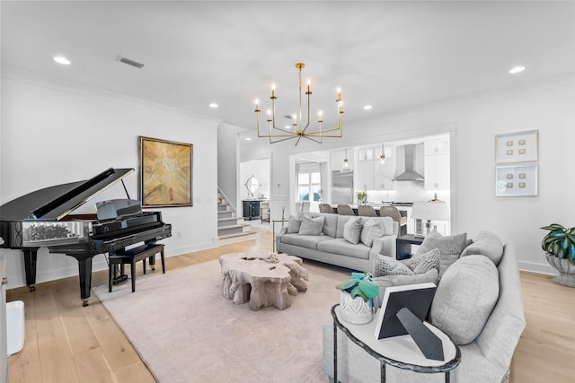 living room featuring light hardwood / wood-style floors, ornamental molding, and an inviting chandelier