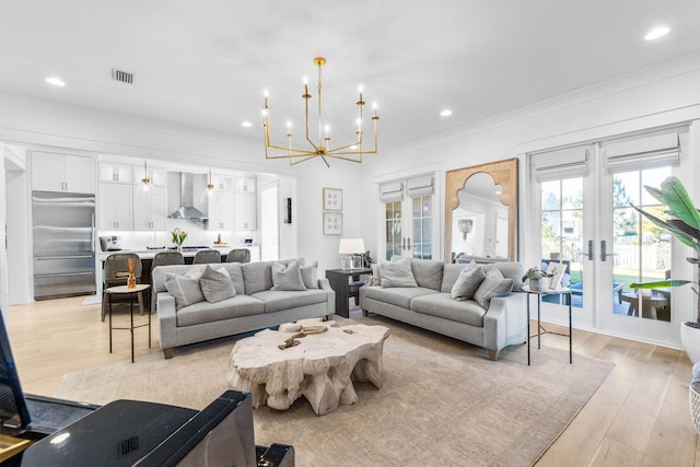 living room featuring a chandelier, french doors, light hardwood / wood-style floors, and ornamental molding