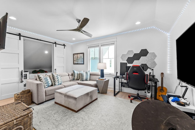 living room featuring a barn door, light hardwood / wood-style flooring, ceiling fan, and lofted ceiling