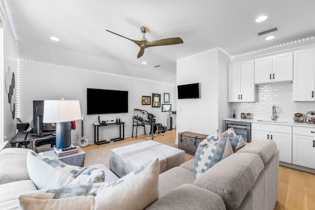 living room with ceiling fan, light hardwood / wood-style floors, sink, and wine cooler