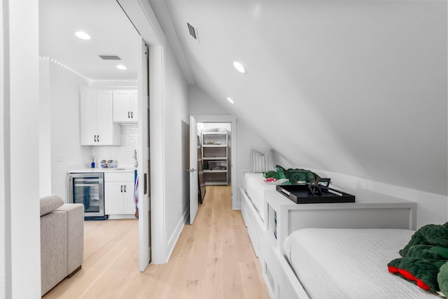 bedroom with sink, beverage cooler, lofted ceiling, and light hardwood / wood-style floors