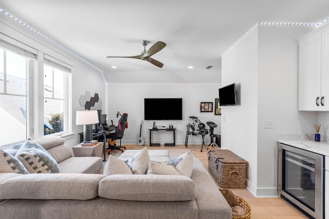 living room featuring ceiling fan, beverage cooler, and light hardwood / wood-style flooring