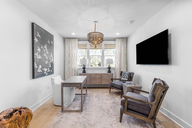 office with light hardwood / wood-style floors and a notable chandelier