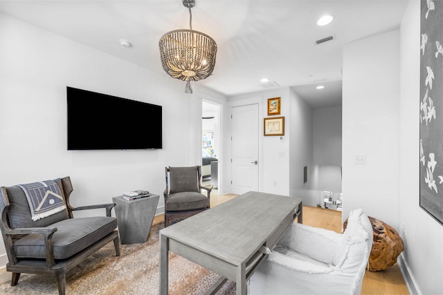 living room with light hardwood / wood-style floors and a notable chandelier