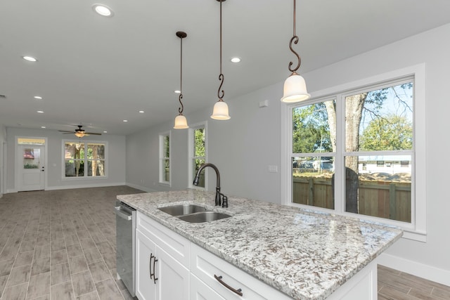 kitchen featuring an island with sink, sink, white cabinets, and pendant lighting