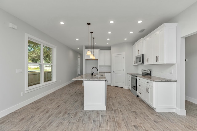 kitchen with pendant lighting, a center island with sink, sink, appliances with stainless steel finishes, and white cabinetry