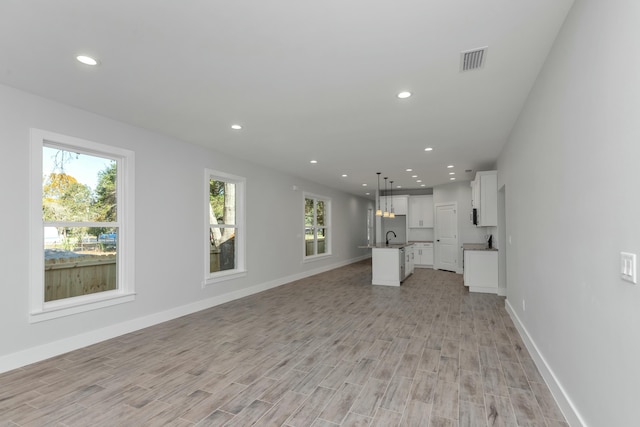 unfurnished living room with light wood-type flooring and sink