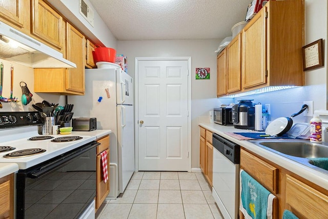 kitchen featuring a textured ceiling, white appliances, light tile patterned floors, and sink