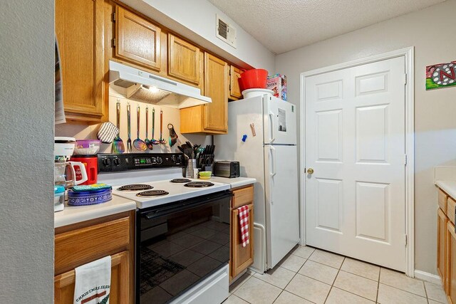 kitchen with white appliances, a textured ceiling, and light tile patterned floors