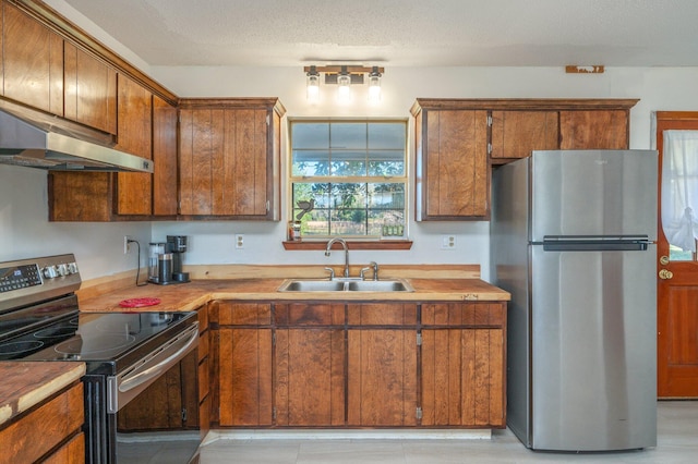 kitchen featuring sink, light hardwood / wood-style flooring, a textured ceiling, appliances with stainless steel finishes, and extractor fan