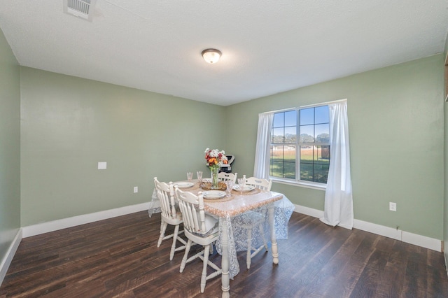 dining room with a textured ceiling and dark hardwood / wood-style flooring