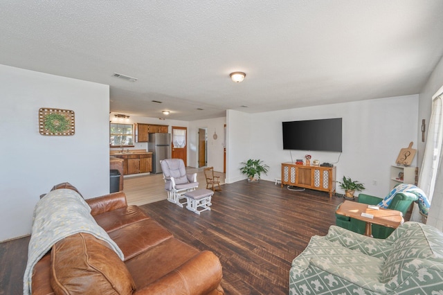 living room with hardwood / wood-style floors, a textured ceiling, and sink