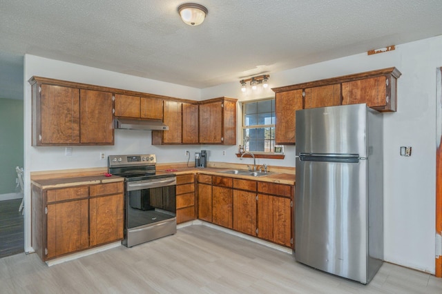 kitchen with sink, appliances with stainless steel finishes, and light hardwood / wood-style flooring