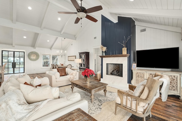 living room featuring vaulted ceiling with beams, a premium fireplace, ceiling fan with notable chandelier, and dark hardwood / wood-style floors