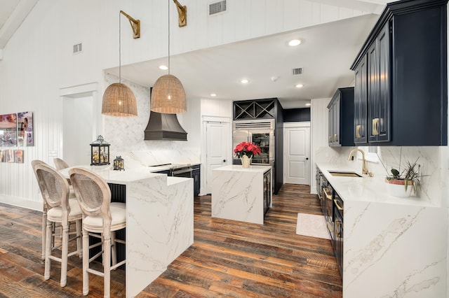 kitchen with tasteful backsplash, dark wood-type flooring, sink, pendant lighting, and a center island