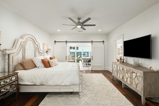 bedroom with a barn door, ceiling fan, dark hardwood / wood-style floors, and access to exterior