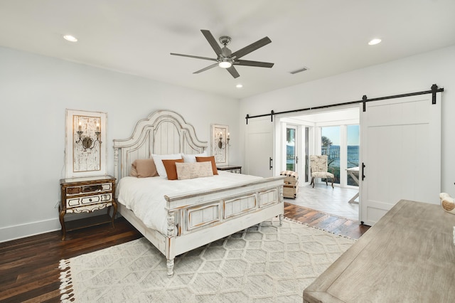 bedroom featuring hardwood / wood-style flooring, ceiling fan, and a barn door