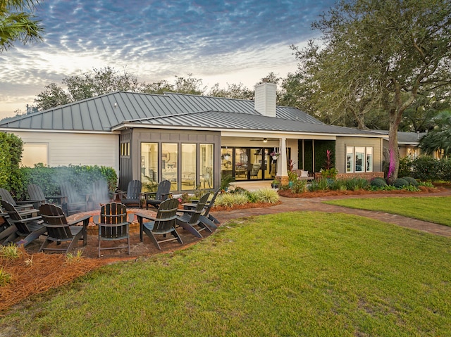 back house at dusk with a yard and a fire pit