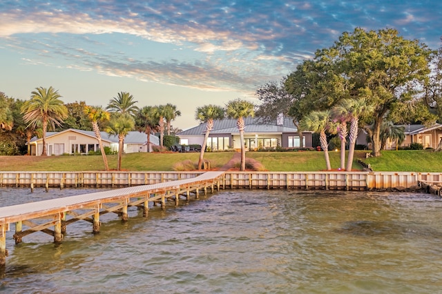 view of dock featuring a water view and a yard