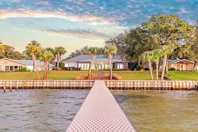 view of dock with a yard and a water view