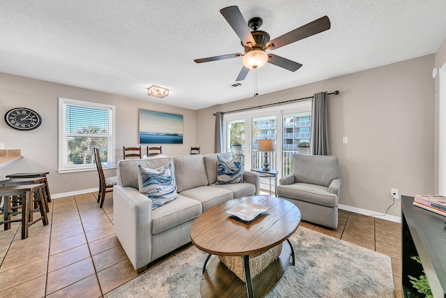 living room featuring a wealth of natural light, light tile patterned floors, a textured ceiling, and ceiling fan