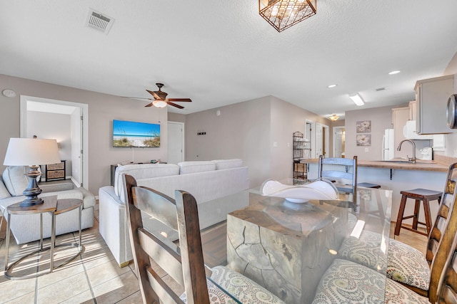 dining space featuring sink, light tile patterned floors, a textured ceiling, and ceiling fan