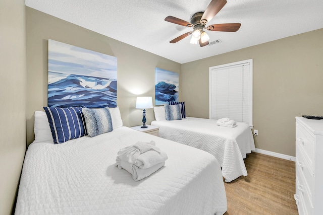 bedroom with ceiling fan, light hardwood / wood-style floors, and a textured ceiling