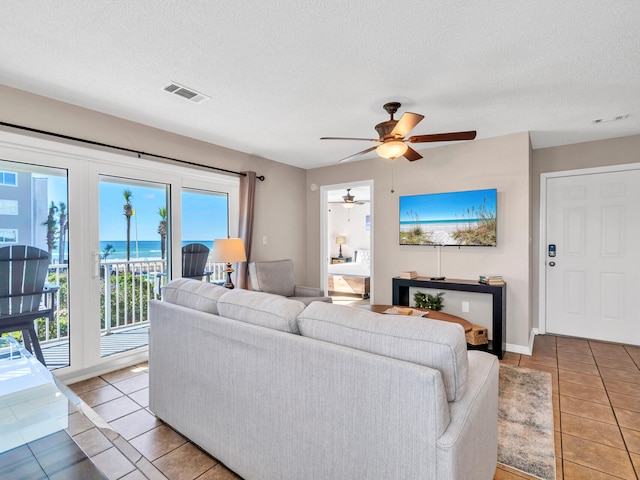 living room featuring ceiling fan, light tile patterned floors, and a textured ceiling