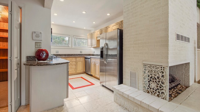 kitchen featuring a fireplace, appliances with stainless steel finishes, light brown cabinets, and light tile patterned floors