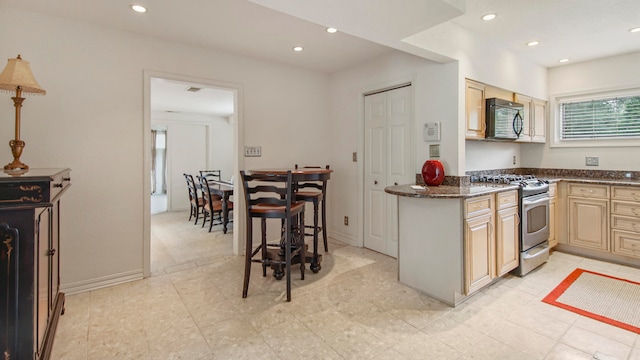 kitchen with stainless steel gas stove and dark stone countertops