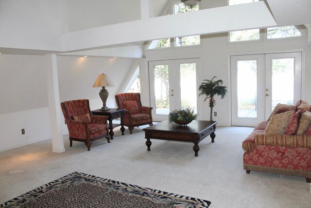 carpeted living room with french doors, high vaulted ceiling, and a healthy amount of sunlight