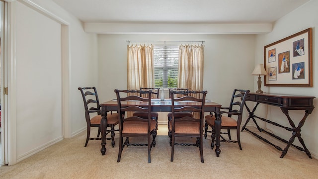 dining space featuring beam ceiling and light carpet