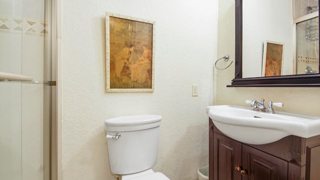 bathroom with a shower with door, vanity, and toilet