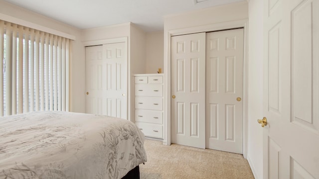 bedroom featuring light colored carpet and two closets