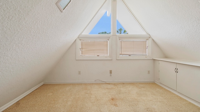 bonus room with lofted ceiling, light colored carpet, and a textured ceiling